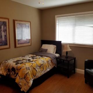 A cozy bedroom with a single bed and warm lighting.