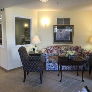 A cozy living room area featuring a floral sofa, patterned chair, and lamps providing ambient light.