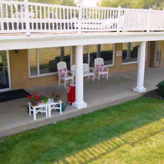 A serene outdoor patio area with white furniture and a view of the lawn.