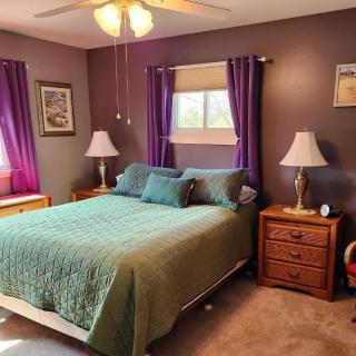 A cozy bedroom with a green bedspread and purple curtains.