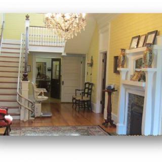Spacious interior with a grand chandelier, elegant staircase, and cozy fireplace.