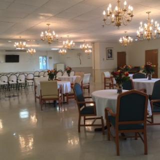 A spacious event venue featuring elegant chandeliers and seating arrangements, ideal for gatherings and celebrations.