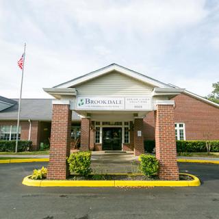 The entrance of a brick building with a flagpole and landscaping.