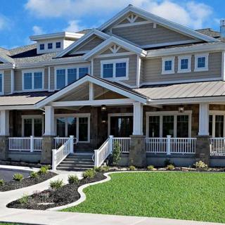 A large, modern house with a spacious porch and well-maintained lawn.