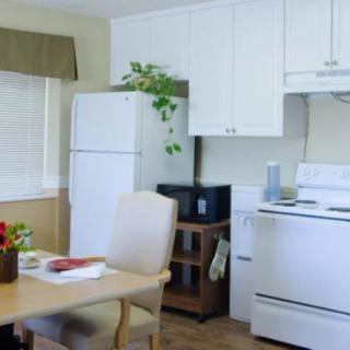 A cozy kitchen with a dining table, stove, refrigerator, and microwave.