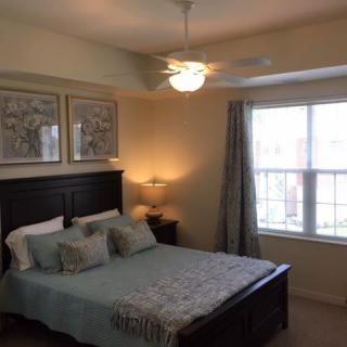 A cozy bedroom with a bed, bedside lamp, and large window.