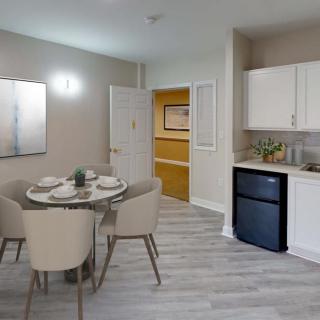 A modern dining area with a small kitchenette, featuring a round table set for four.