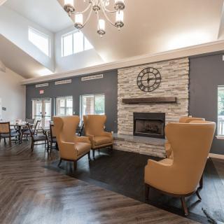 A cozy lounge area featuring comfortable armchairs, a fireplace, and ample natural light.