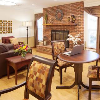 A cozy living room with a brick fireplace, wooden furniture, and warm decor.