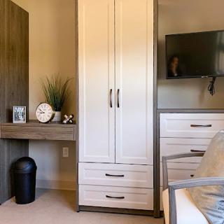A modern home office setup featuring a sleek desk, storage cabinets, and a television.