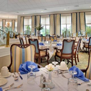 An elegant dining room with neatly arranged tables and chairs, complete with tasteful decor and large windows.