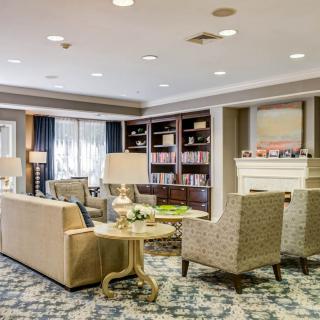 A cozy living room area with armchairs, a sofa, bookshelves, and a fireplace.