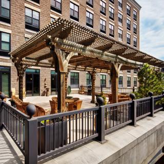 Outdoor seating area with a wooden pergola on a building patio.