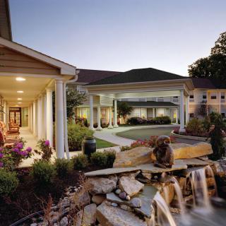 A serene outdoor view showcasing a beautifully landscaped garden and a building with a columned porch at dusk.