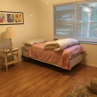 A cozy bedroom with a single bed and a large window letting in natural light.