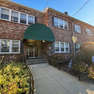 A cozy brick apartment building with a welcoming green awning at the entrance.
