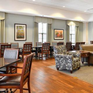 A spacious and well-lit lounge area featuring a mix of tables, chairs, and comfortable seating.