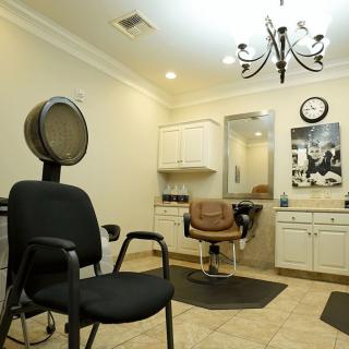 A well-equipped hair salon interior with chairs, a mirror, and a hair dryer.