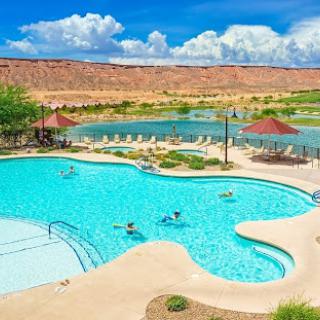A picturesque resort pool surrounded by nature and clear blue skies.