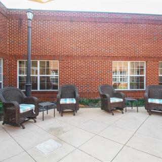 A cozy outdoor patio area with wicker chairs and a brick wall backdrop.