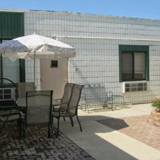 A cozy outdoor seating area with a table, chairs, and an umbrella beside a building.