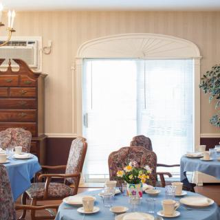 A well-decorated dining room with multiple tables set for a meal, featuring blue tablecloths and elegant chairs.