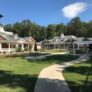 A peaceful community setting with well-maintained pathways and buildings under a clear blue sky.