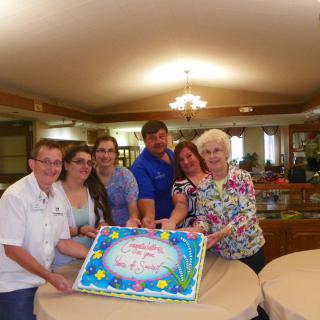 A group of people celebrating with a colorful cake indoors.