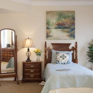 A cozy bedroom with a single bed, wooden furniture, and a decorative painting on the wall.