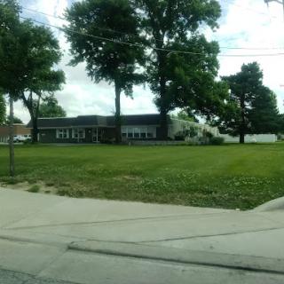 A view of a building surrounded by trees and open grass.
