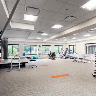 Spacious gym with various exercise equipment and bright natural lighting.