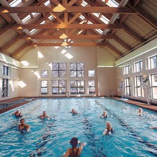 A group of people enjoying a swim session in an indoor pool with natural lighting.