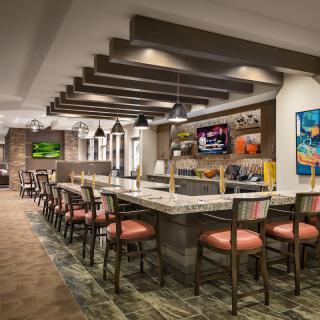 A modern restaurant interior featuring bar seating and televisions.