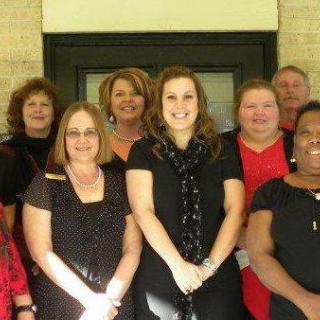 A group of people posing for a photo indoors, smiling and standing together.