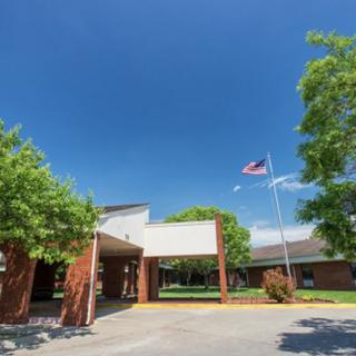 A school building entrance with an American flag and clear blue sky.