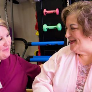 Two women chatting in a room with exercise equipment.