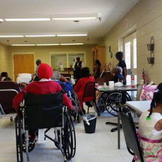 A community gathering in a care facility where elderly individuals engage in social activities.