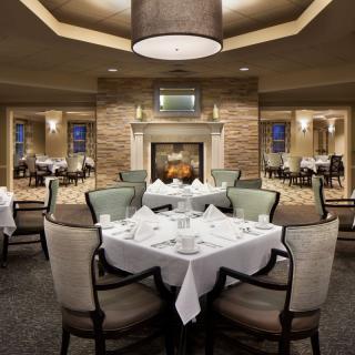 An elegant restaurant dining room with a central fireplace and beautifully set tables.