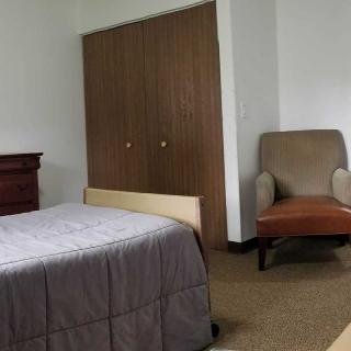 Simple bedroom with a bed, chair, and closet.