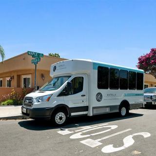 A shuttle bus parked on a street in an urban neighborhood during the day.