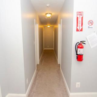 A well-lit hallway with a fire extinguisher mounted on the wall.
