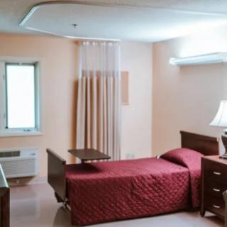 A hospital room with a single bed, wooden furniture, and a soft ambient light.