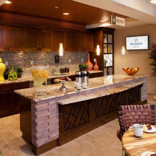 A modern kitchen with wooden cabinetry and a stylish countertop, featuring pendant lighting and decorative accents.