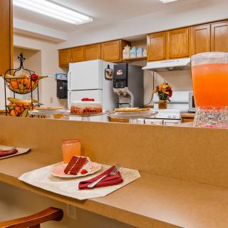A cozy kitchen with a countertop set for dining, featuring cake slices and a pitcher of juice.