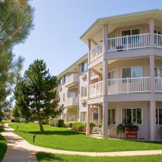 A sunny day view of a residential apartment building with balconies and surrounding greenery.