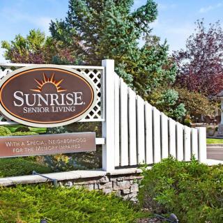 Entrance sign for Sunrise Senior Living surrounded by lush greenery.