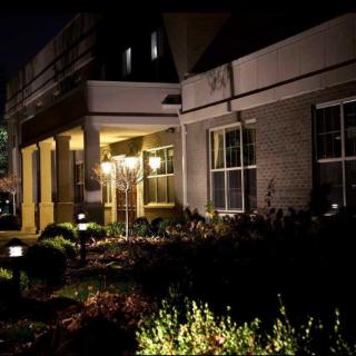 A well-lit building entrance at night surrounded by landscaping.