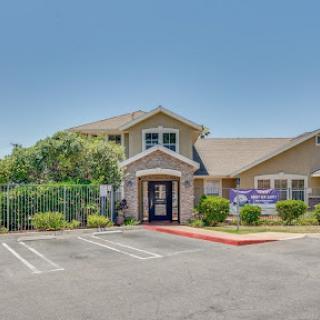 A welcoming entrance to a commercial building with ample parking and greenery.