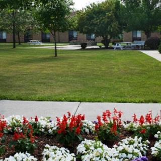 A beautiful garden with vibrant flowers and a well-maintained lawn, surrounded by trees and pathways.