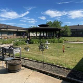 A sunny garden with a gazebo and surrounding buildings.